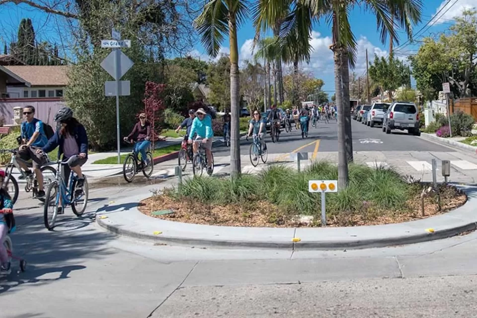Group of people and kids biking through small roundabout in Long Beach, California.